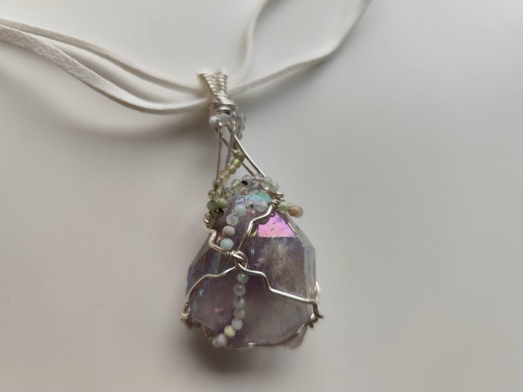 Ręcznie wykonany wisiorek z naturalnego ametystu, misternie opleciony drutem miedzianym pokrytym srebrem - widok z góry na wisiorek.