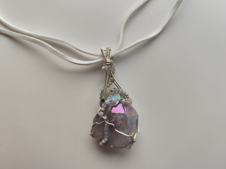 Ręcznie wykonany wisiorek z naturalnego ametystu, misternie opleciony drutem miedzianym pokrytym srebrem - widok pod kątem na wisiorek.