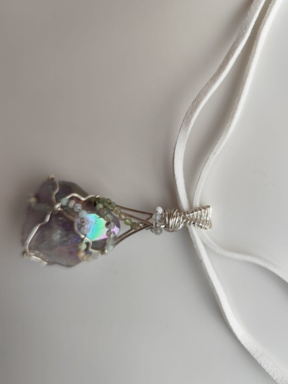 Ręcznie wykonany wisiorek z naturalnego ametystu, misternie opleciony drutem miedzianym pokrytym srebrem - widok pod kątem na wisiorek.