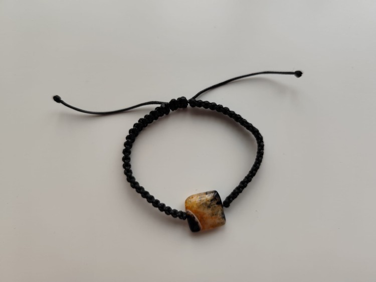 Bransoletka z kamieniem agatu w odcieniach czerni i jasnej pomarańczy na czarnym sznurku - widok z góry