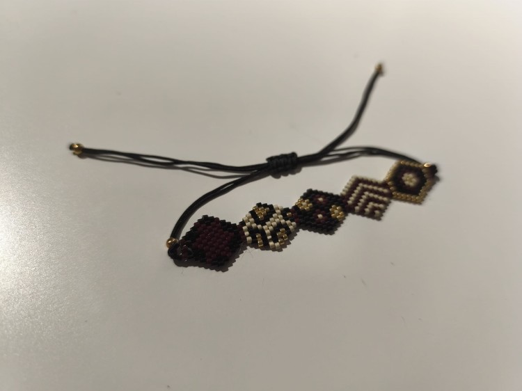 Bransoletka z koralików MIYUKI w kolorach czerni, bieli, brązu i złota na czarnym sznurku - widok pod kątem