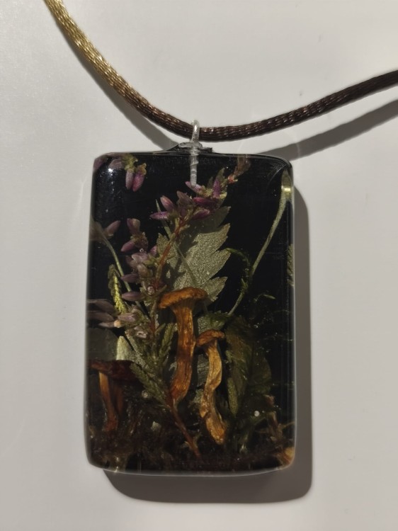 Zawieszka prostokątna z ciemnej żywicy z zatopioną florą leśną - zbliżenie