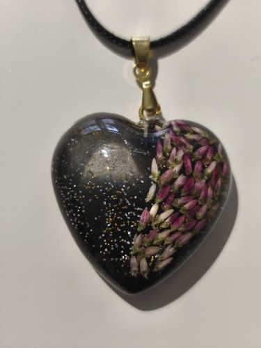 Zawieszka w kształcie serca z nasionami wrzosu i brokatem zatopionymi w ciemnej żywicy - zbliżenie
