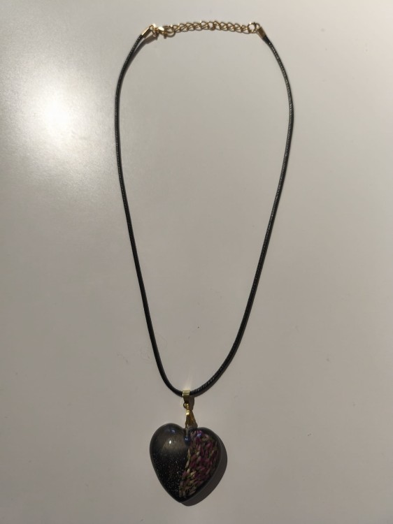Zawieszka w kształcie serca z nasionami wrzosu i brokatem zatopionymi w ciemnej żywicy