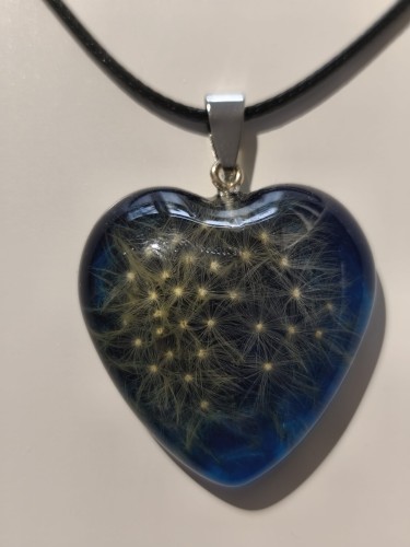 Zawieszka w kształcie serca z nasionami dmuchawca zatopionymi w niebieskiej żywicy - zbliżenie