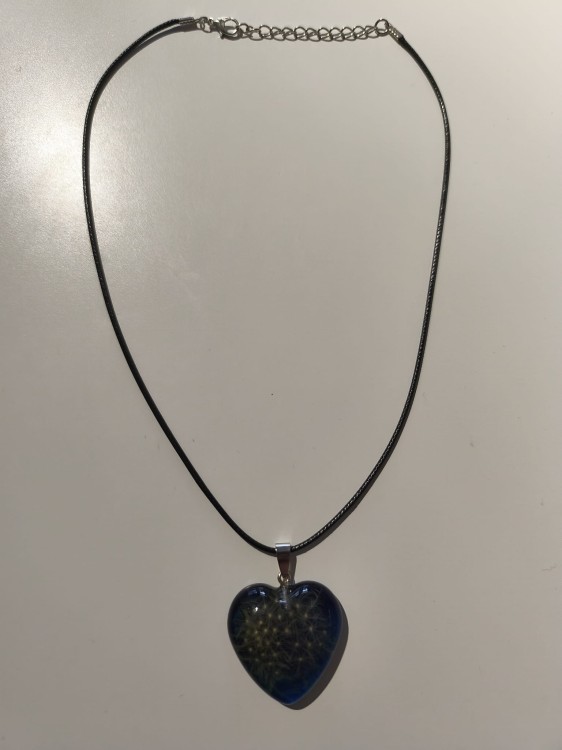 Zawieszka w kształcie serca z nasionami dmuchawca zatopionymi w niebieskiej żywicy