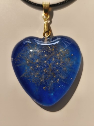Zawieszka w kształcie serca z nasionami dmuchawca i złotym brokatem zatopionymi w niebieskiej żywicy - zbliżenie