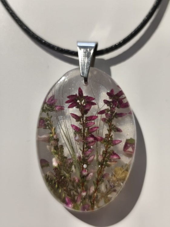 Zawieszka z kwiatami wrzosu zatopionymi w jasnej żywicy - zbliżenie