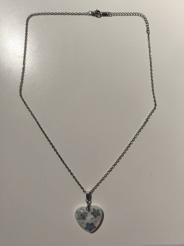 Zawieszka w kształcie serca z suszonymi niezapominajkami zatopionymi w jasnej żywicy