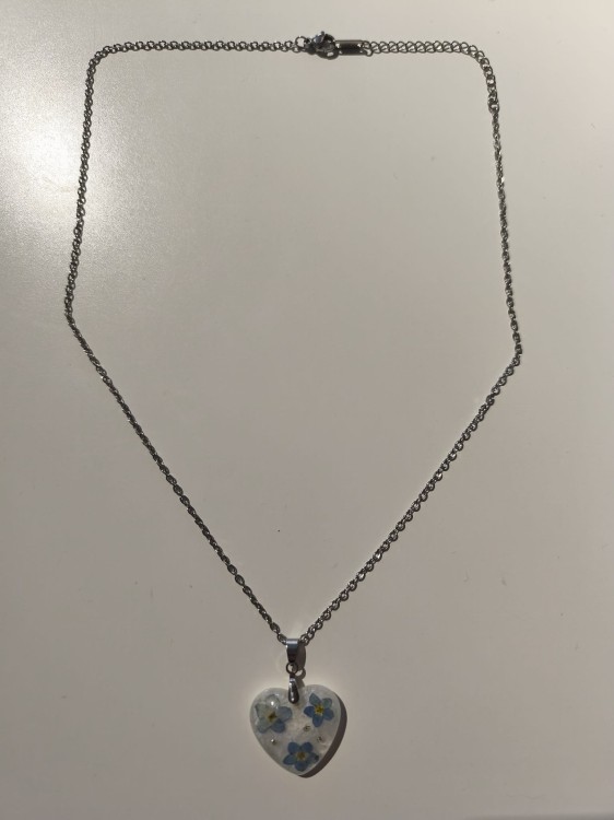 Zawieszka w kształcie serca z suszonymi niezapominajkami zatopionymi w jasnej żywicy